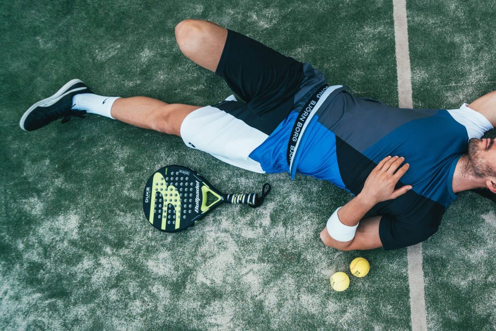 Hombre acostado después de jugar pádel